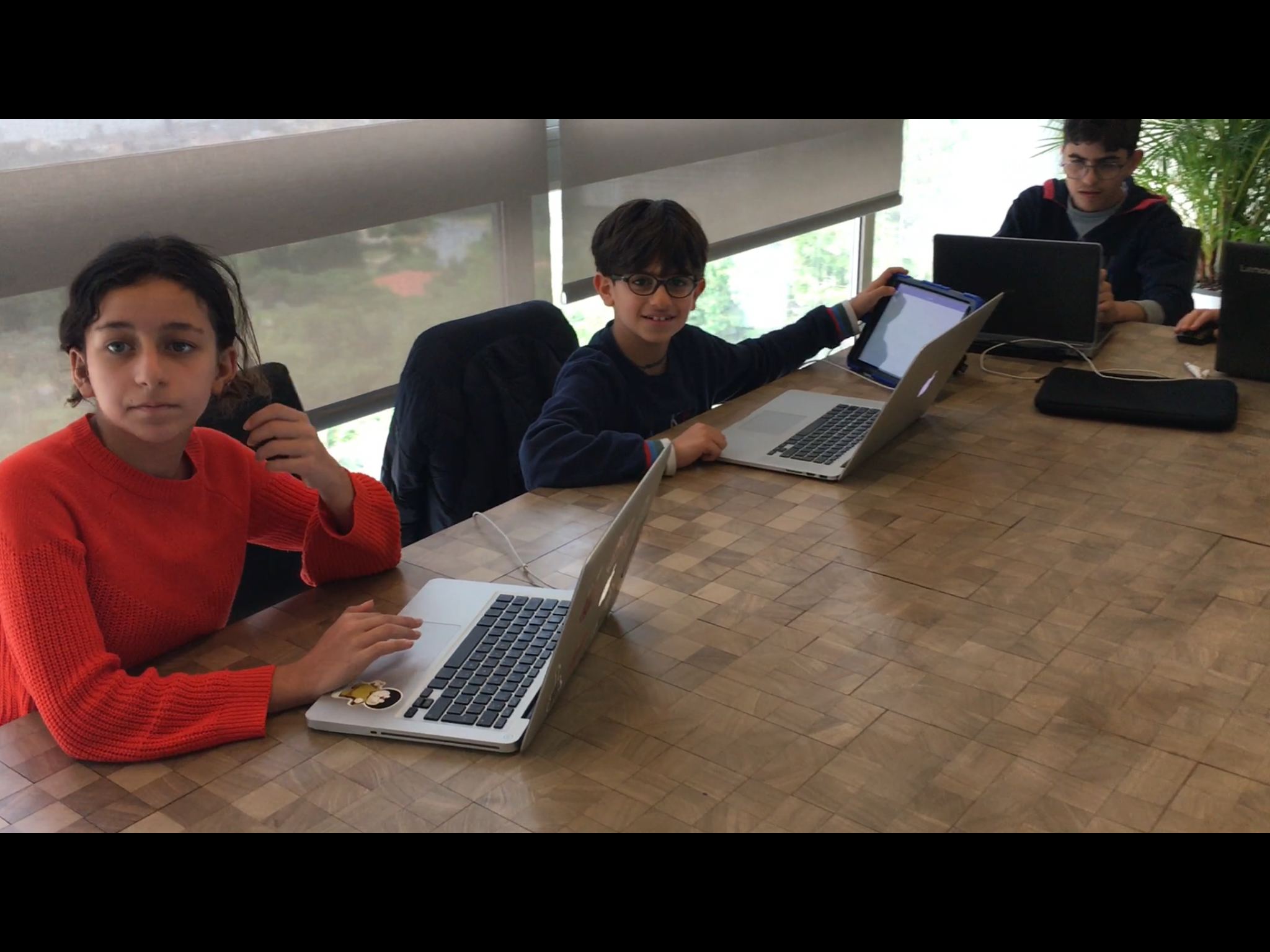 Young learners using laptops and a tablet in a technology classroom
