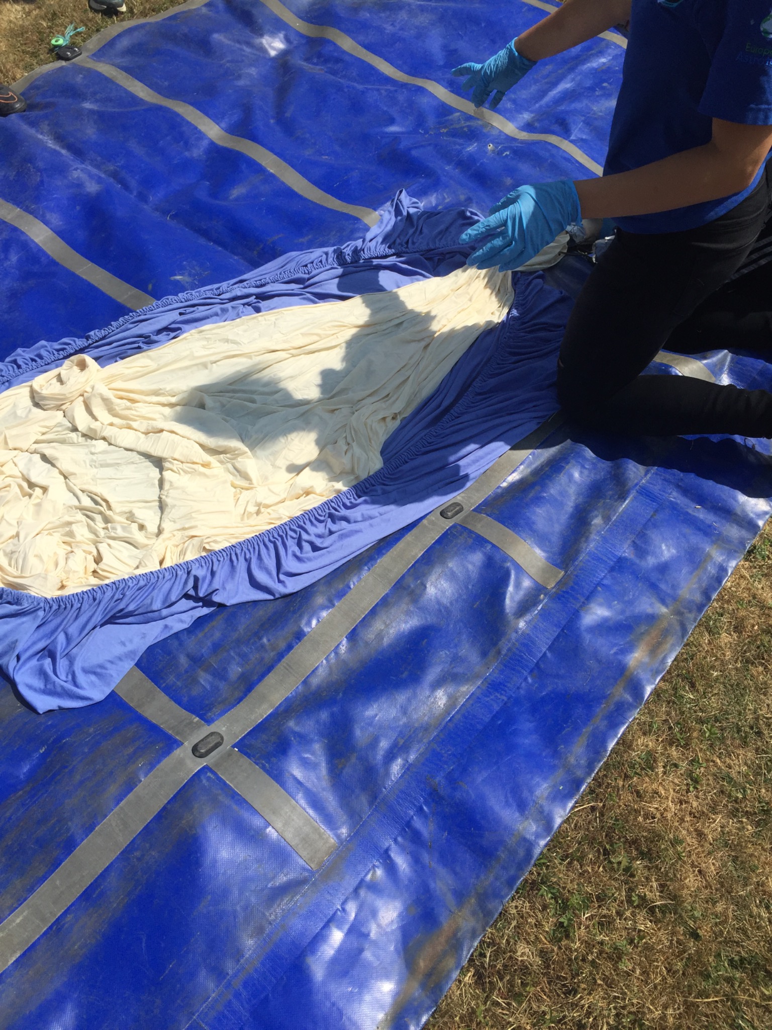 Gloved team members carefully handling the uninflated balloon material
